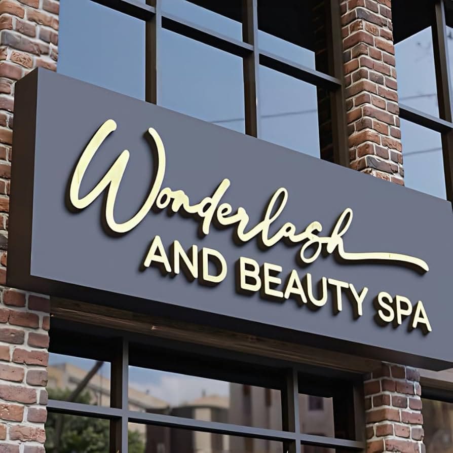 A modern, stylish sign displaying "Wonderlash and Beauty Spa" mounted on a brick building facade with large windows in the background.